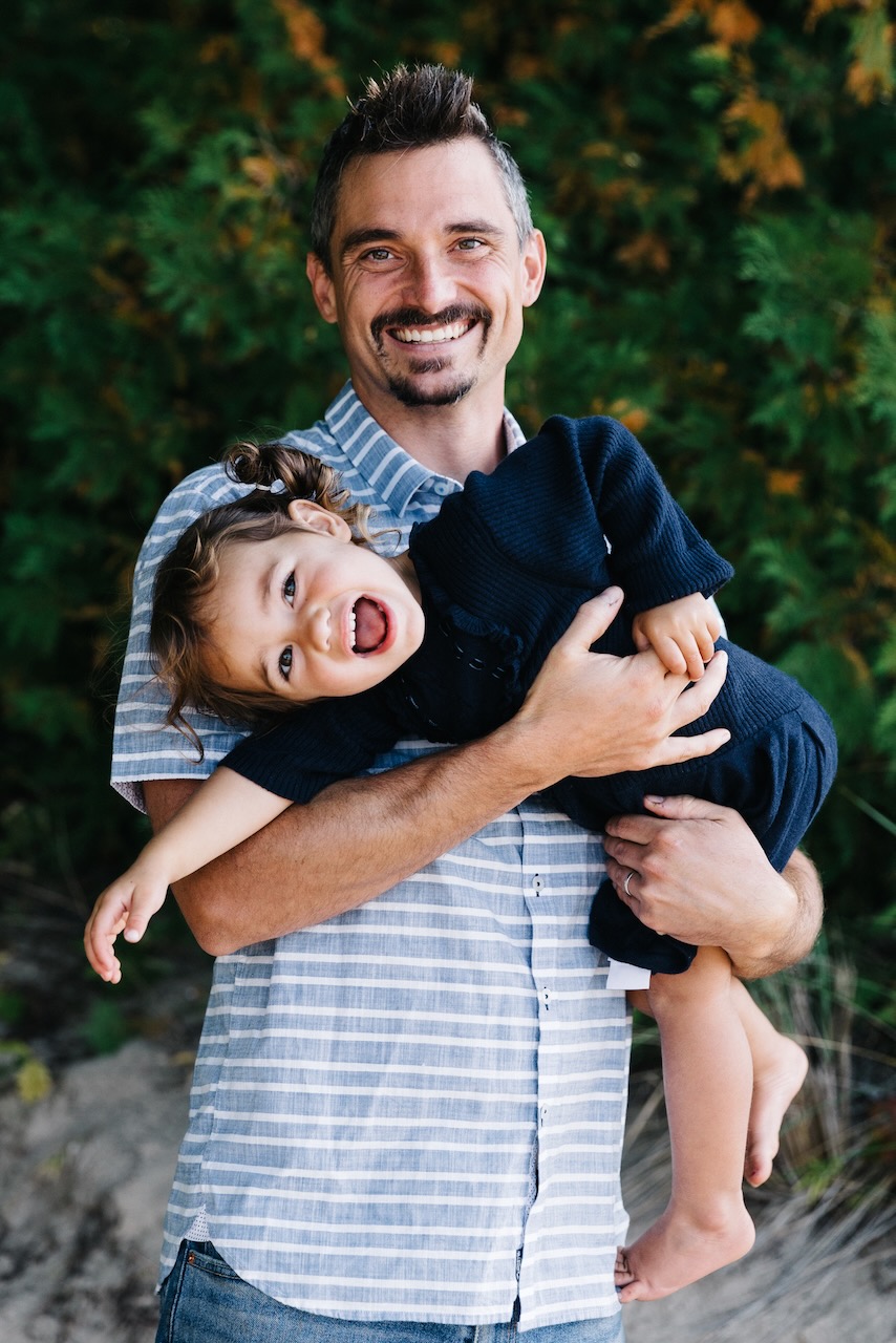 Jason laughing with his daughter Jude in his arms
